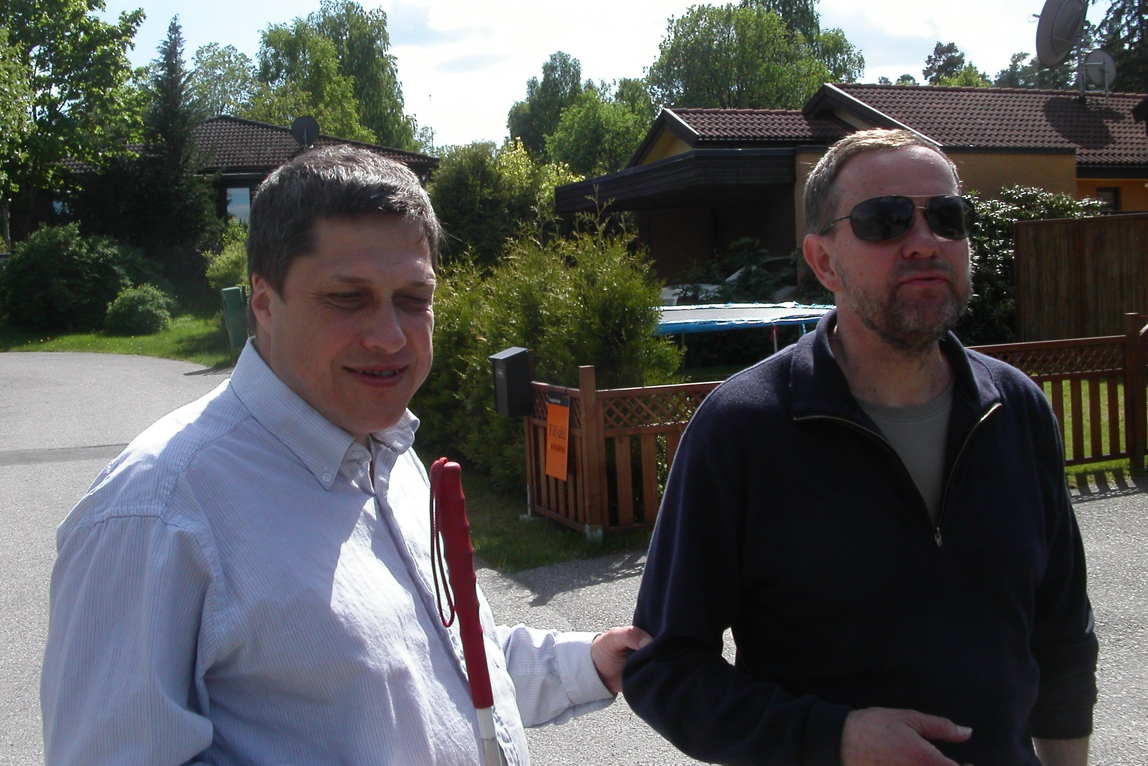 Kjell Andersson och ledsagaren Bengt Fredriksson i ett radhusområde i sommargrönska.